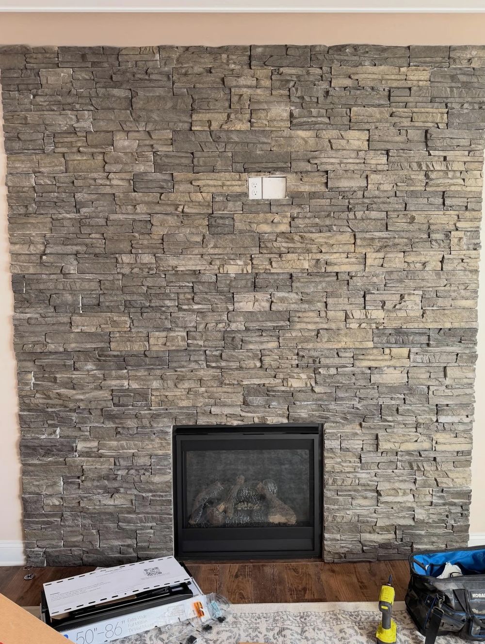 Stacked-stone fireplace wall in a Halifax living room before TV mounting, outlet already at TV height
