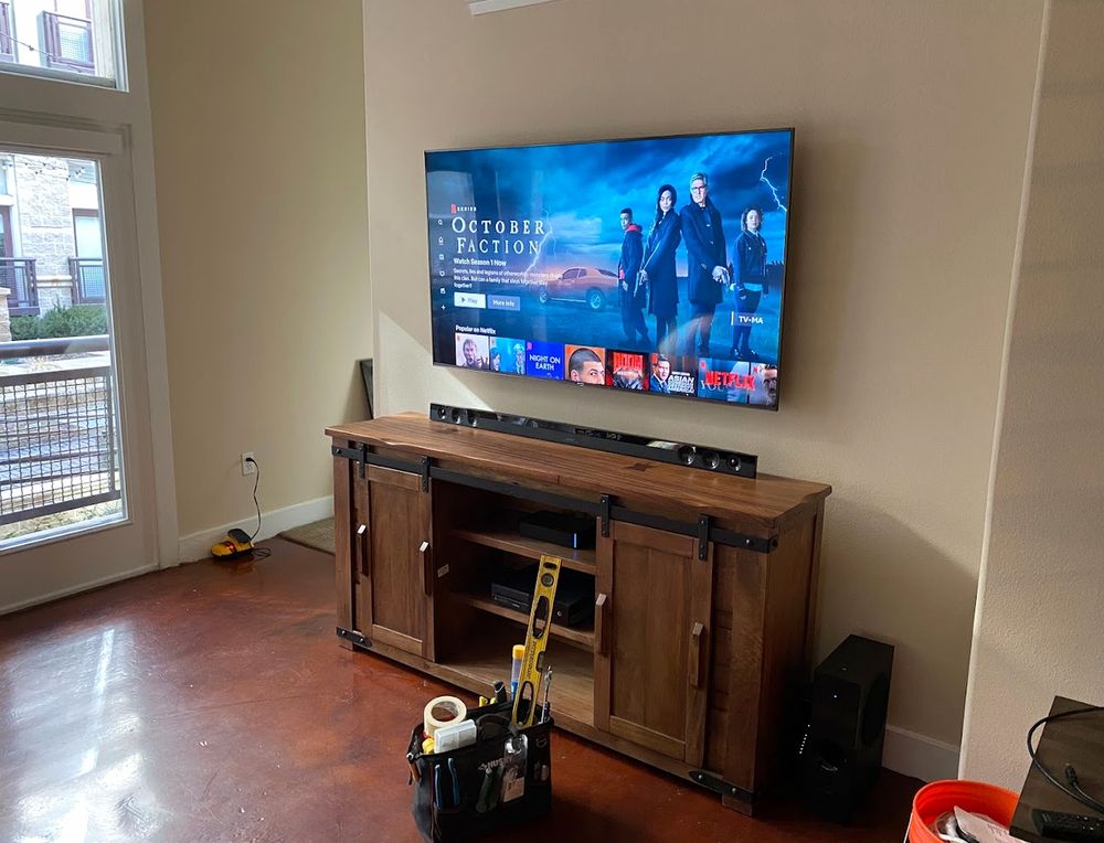 TV wall-mounted above a wooden media console with a soundbar, Halifax apartment