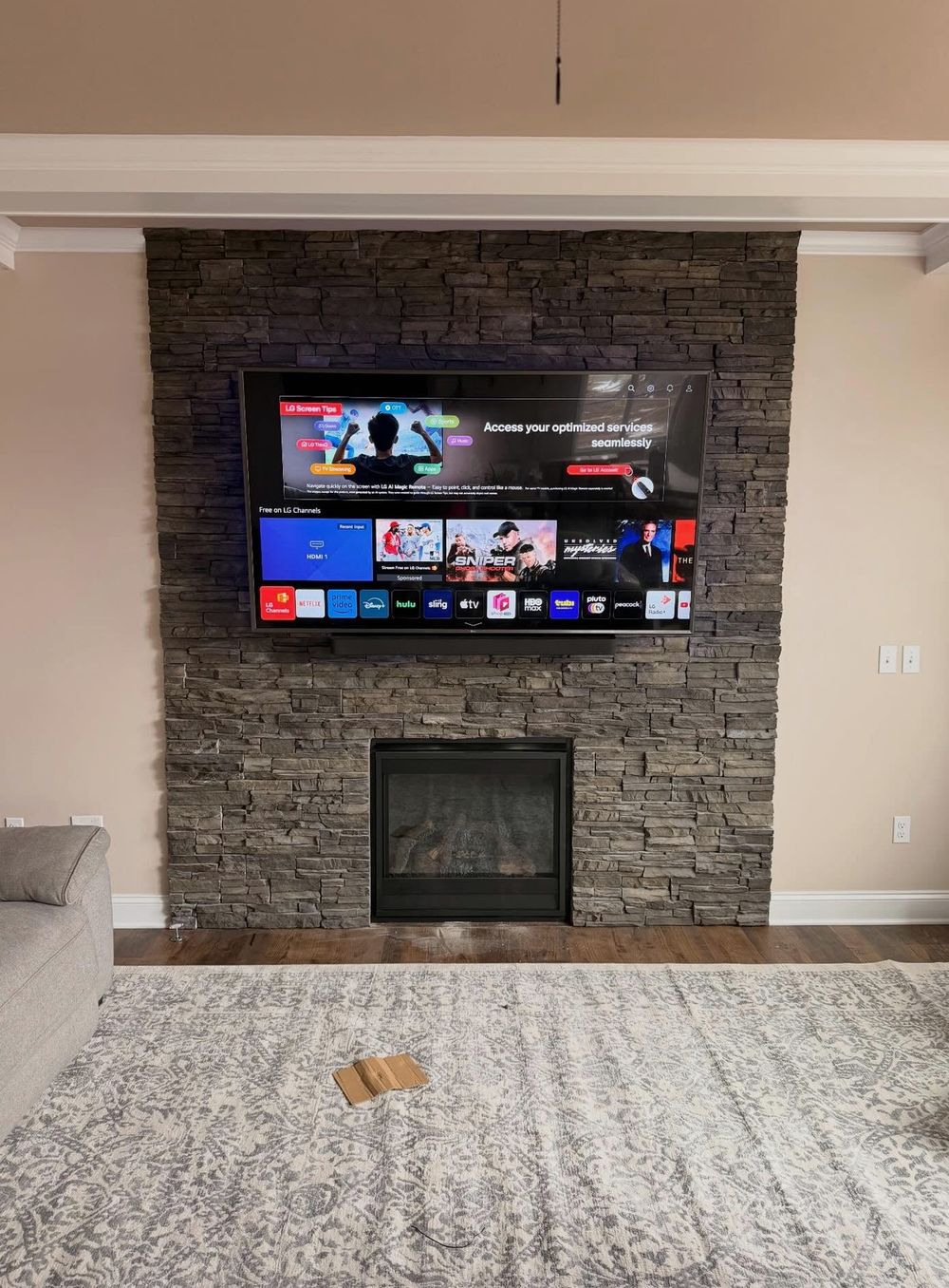 LG smart TV mounted above a stacked-stone gas fireplace in Halifax, no visible cables