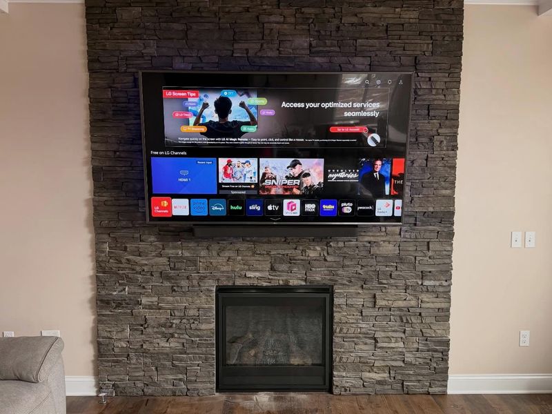 LG smart TV mounted above a stacked-stone gas fireplace in Halifax, no visible cables