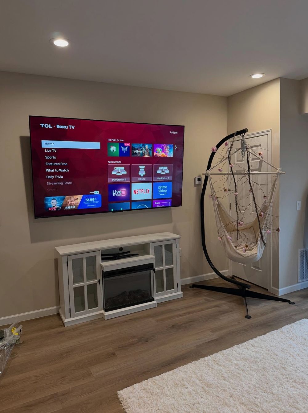 TCL Roku TV wall-mounted above a white electric fireplace console in a Halifax living room