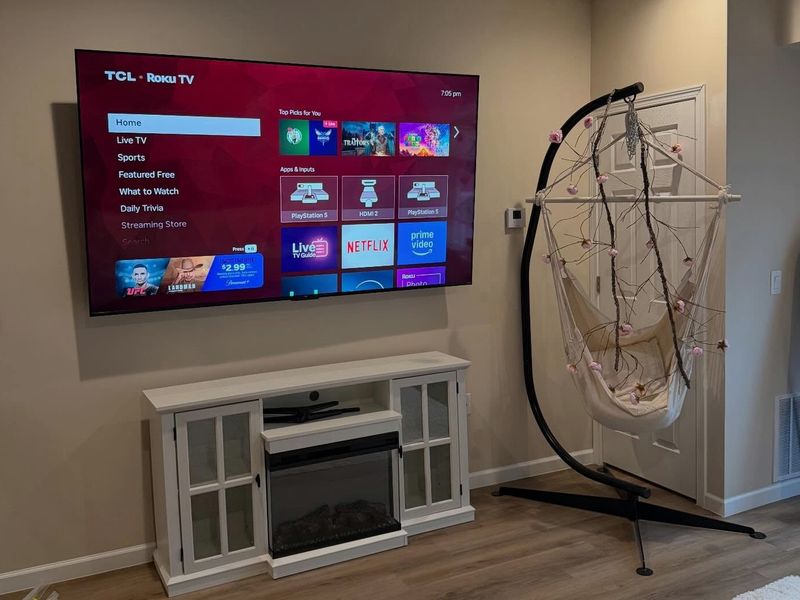 TCL Roku TV wall-mounted above a white electric fireplace console in a Halifax living room