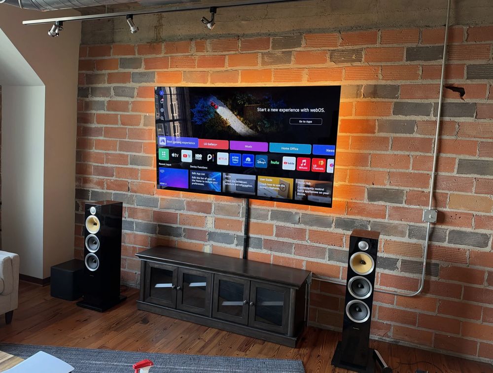 TV mounted on an exposed brick wall in a Halifax loft with LED backlight and a cable channel down to the console